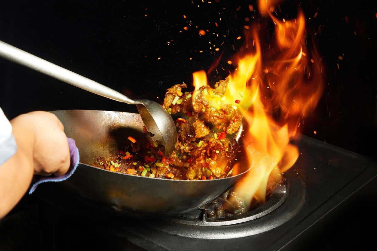 Chef executing traditional wok stir-fry technique