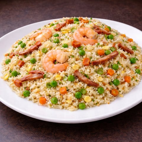 Shrimp fried rice on white plate with green peas, diced carrots, and egg
