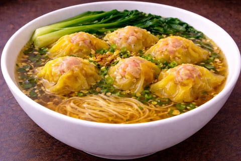 Bowl of wonton noodle soup with shrimp dumplings, thin egg noodles, and bok choy in clear broth