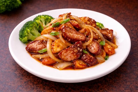 Plate of stir-fried sausage with onions and green onions, served with steamed broccoli on white plate