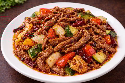 Spicy stir-fried beef with diced vegetables including peppers, zucchini, and dried chilies on a white plate