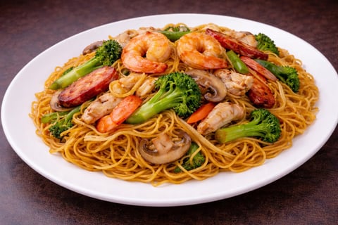Stir-fried noodles with shrimp, mushrooms, broccoli, and red bell peppers on a white plate